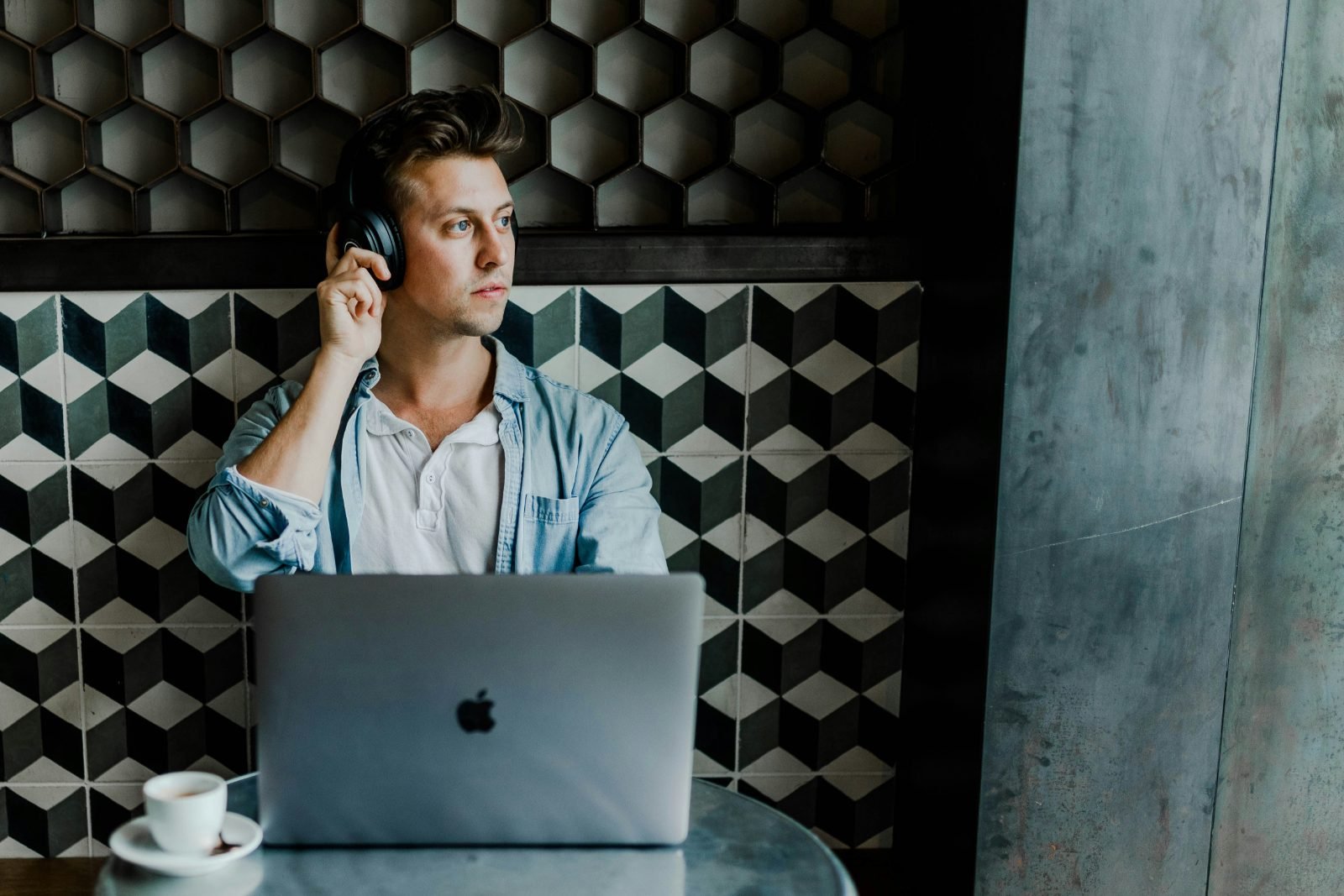 A founder with headphones at a laptop in a café